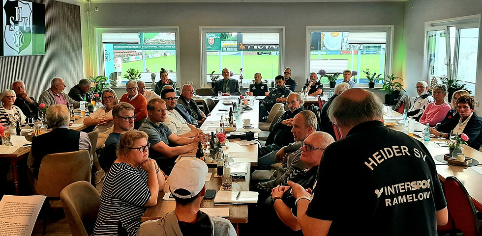 Mitgliederversammlung des Heider SV im HSV-Kasino mit zahlreichen Teilnehmenden. Im Hintergrund Blick auf den Sportplatz.