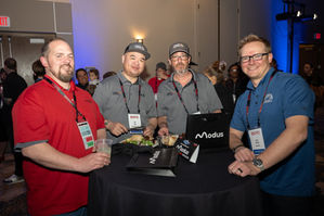 Four men at Modus event standing at a small table, smiling.