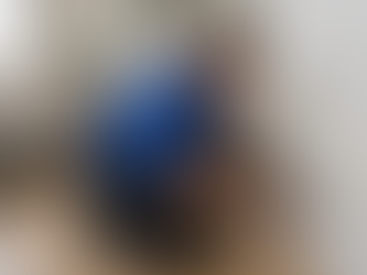 Professional restoration technician in a blue polo kneeling in a modern living room, using a moisture meter to inspect baseboards and lower wall areas for hidden moisture, with subtle dampness visible near the flooring under soft natural daylight