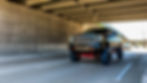 lifted truck driving under bridge