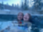 The girls in a hot tub with snowy trees in the background. The scene is joyful and wintry.