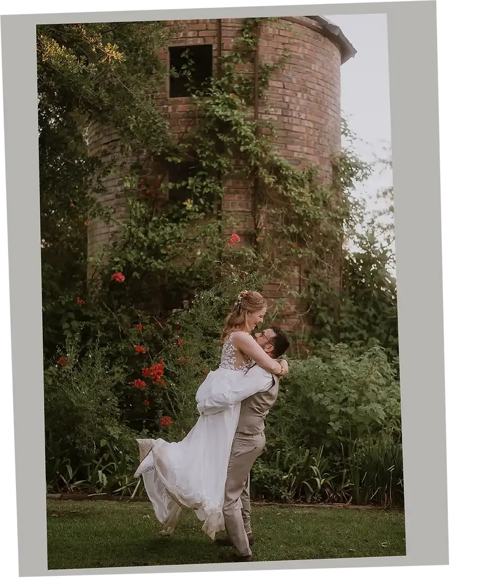 Groom picking up his bride and spinning her in front of an old French mill at De Meyer in Cape Town