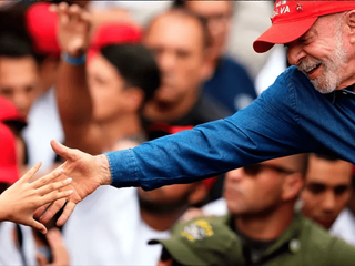 O presidente eleito do Brasil, Lula, dá a mão direita para um apoiador durante comemoração da vitória