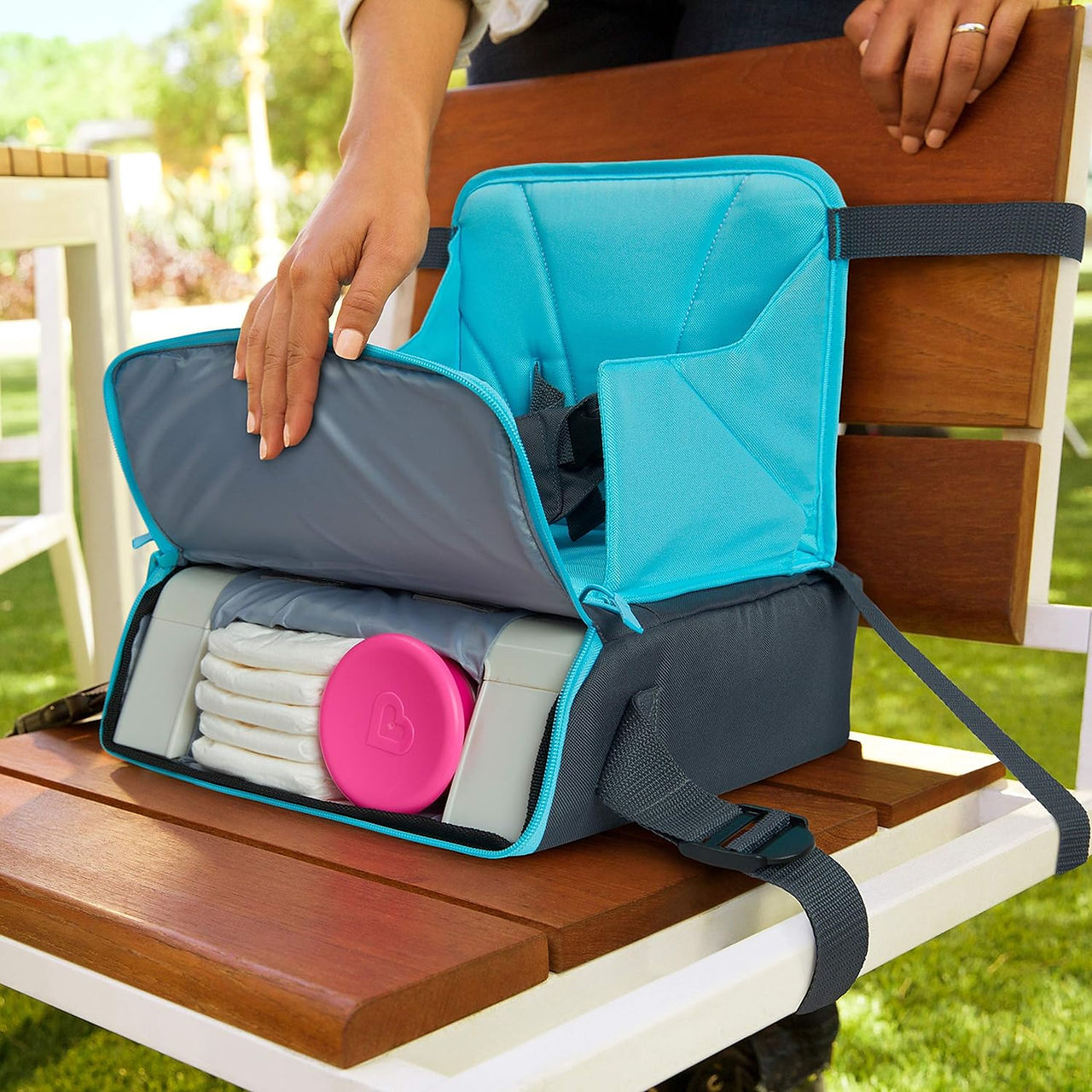 The Munchkin Baby Travel High Chair attached to a chair with the storage capabilities shown