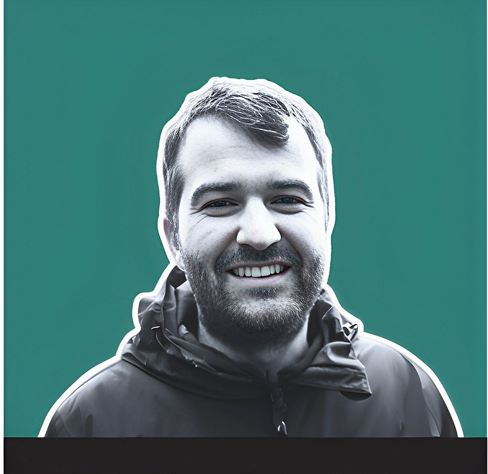 Headshot of a smiling man with a beard on teal background.