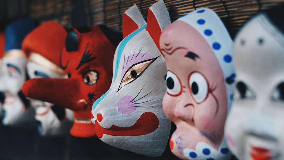 paper mache masks of a doll, old woman, cat and devil lined up