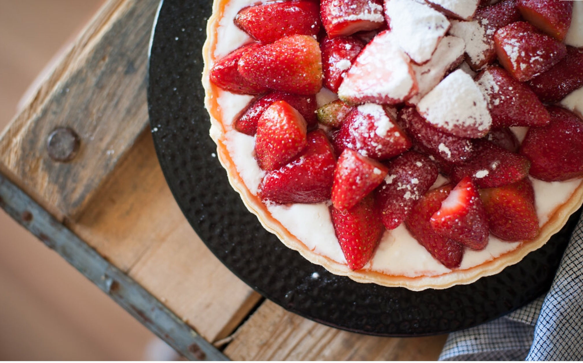 Strawberry tart presented on a black plate. 