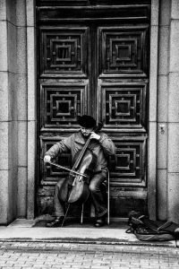 b&w photograph of a man playing his cello busking in  the doorway of what is probably a cathedral.  The doos is wooden and elaborately carved. He is playing with deep concentration and love of his music. What is the one loving, dedicated thing that you can do for your relationship today? Now.