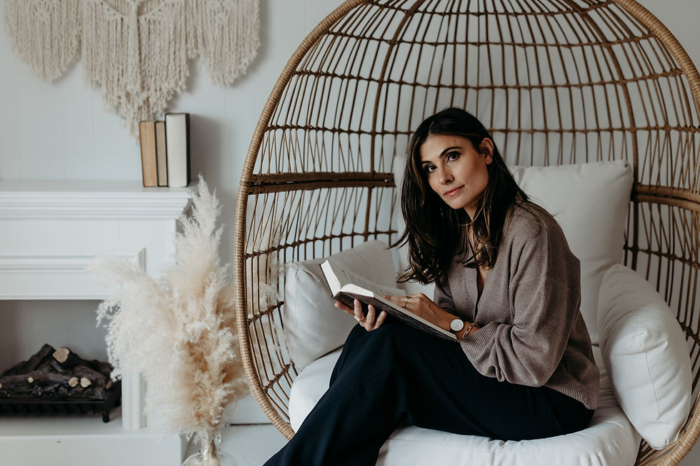 Freelane editor Michelle Meade sitting in a large rattan eggshaped chair, reading a book. She is looking toward the camera while holding a novel open in her hands