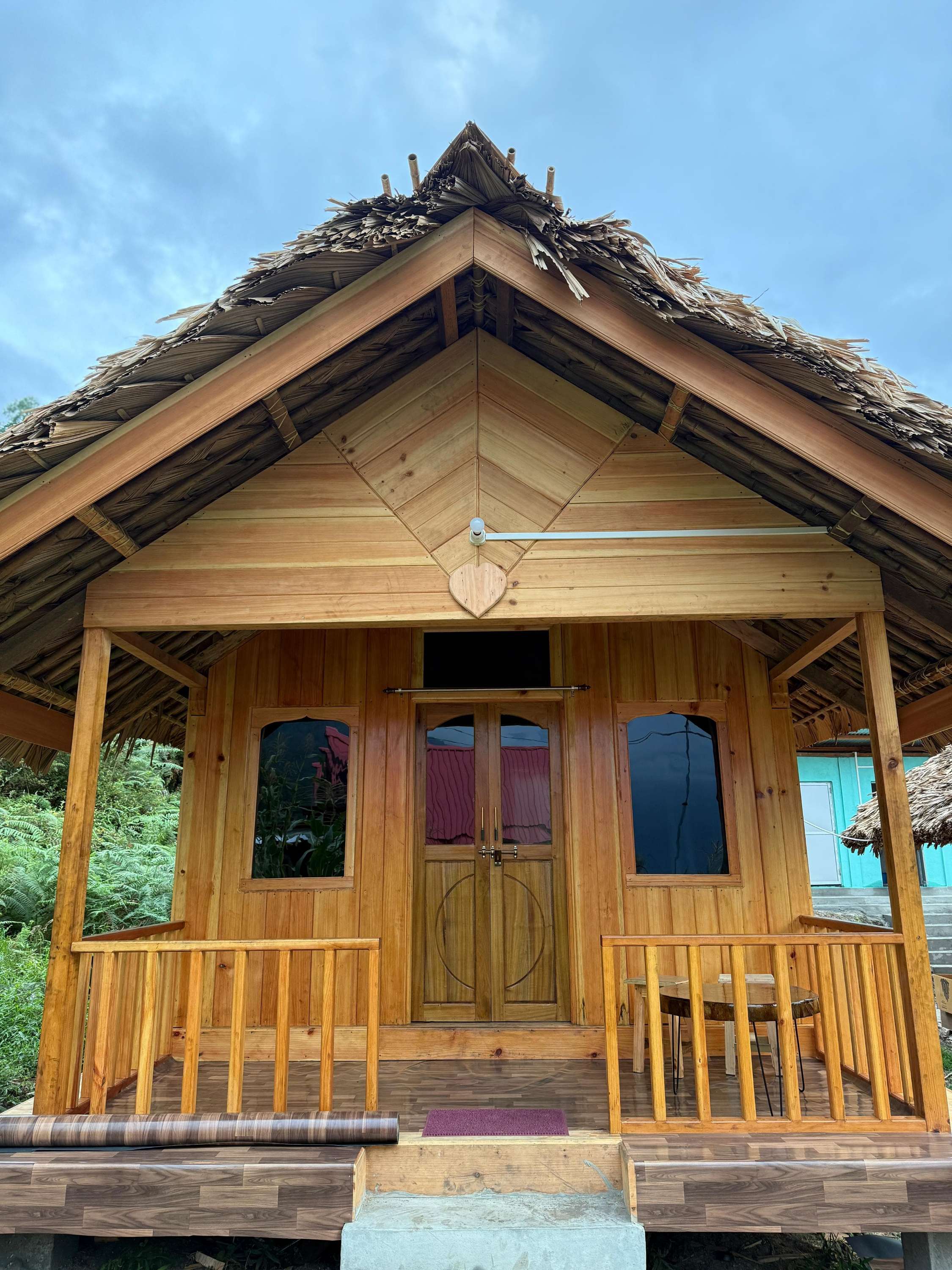 Acheso Homestay Anini exterior view with traditional architecture surrounded by lush green mountains in Arunachal Pradesh