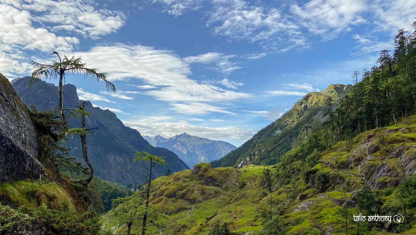 Panoramic view of Dibang Valley and Zawru Valley under a cloudy sky with sunlight breaking through.