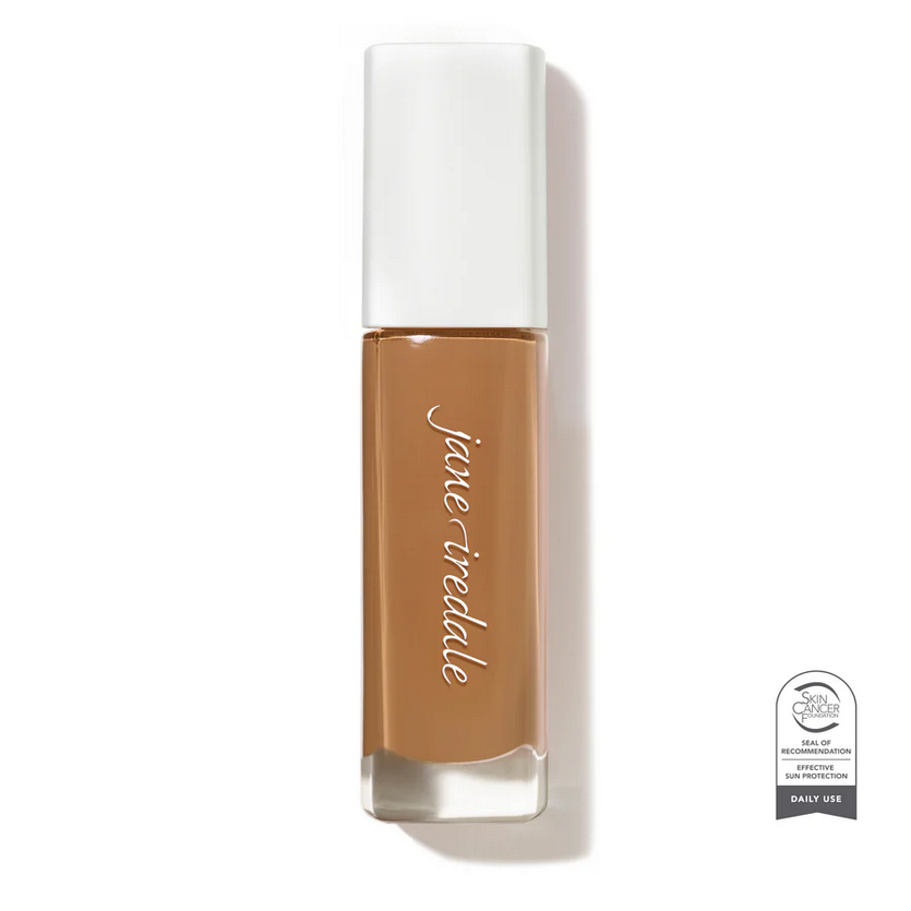 Clear glass make up bottle with a white top containing medium dark face foundation.