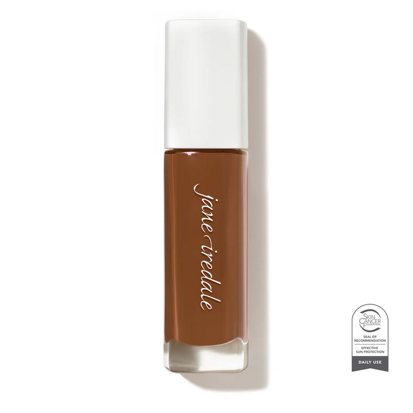 Clear glass make up bottle with a white cap containing a deep dark Face foundation.