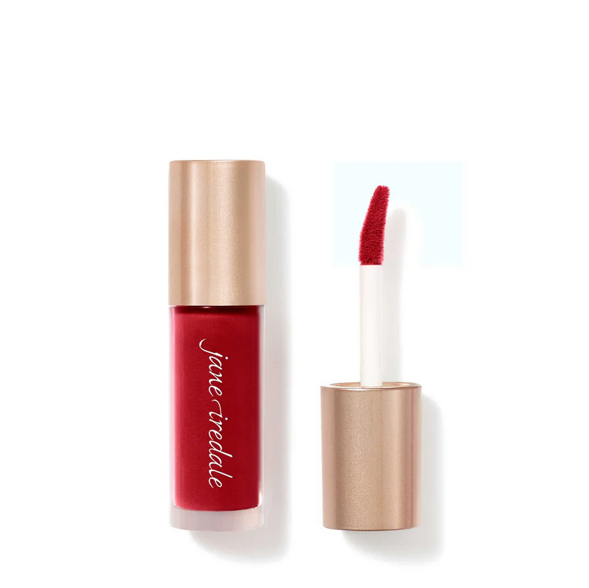 A clear bottle of makeup with a lip applicator.