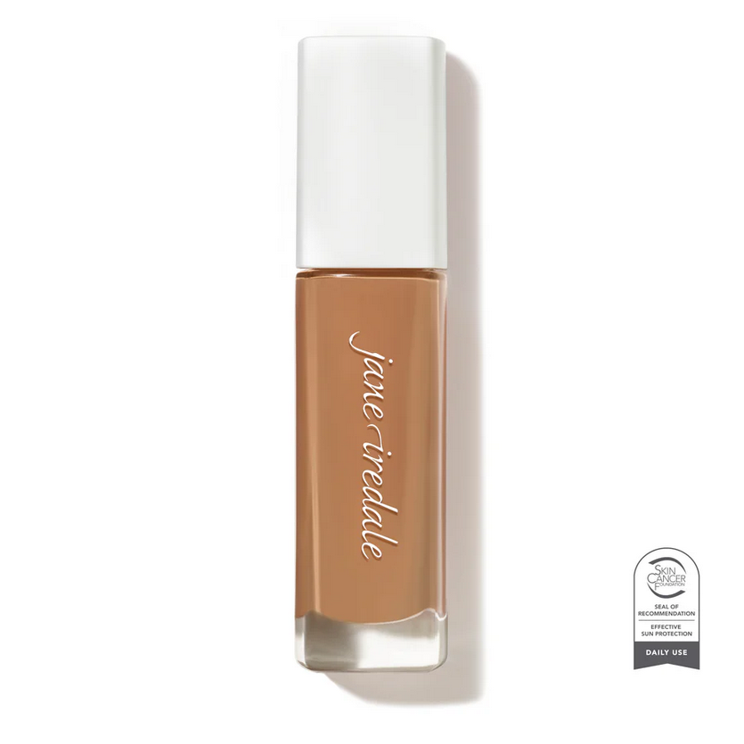 Clear glass make up bottle with a white top containing a medium shade face foundation.