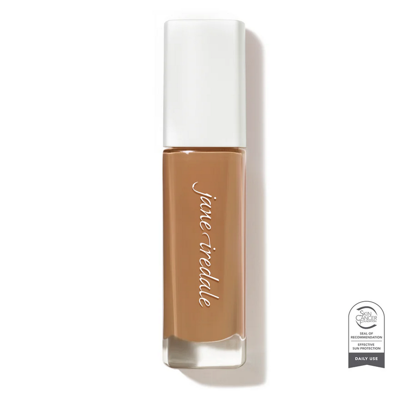 Clear glass make up bottle with a white top containing a medium dark face foundation.