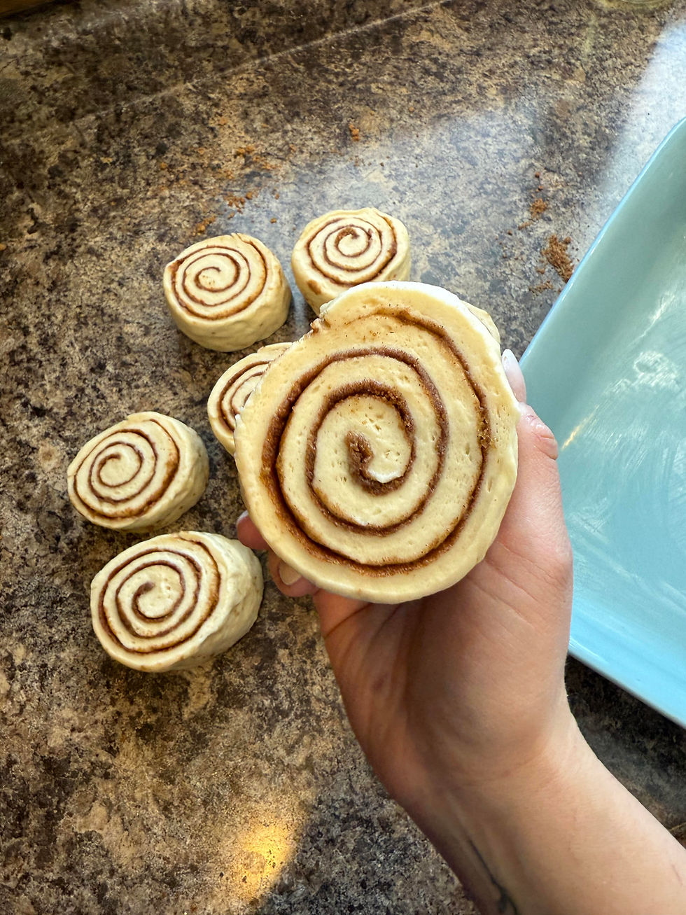 Dough balls in a glass dish and skillet, brushed with egg wash, on a gray tablecloth. Egg wash in a jar beside, ready to bake.