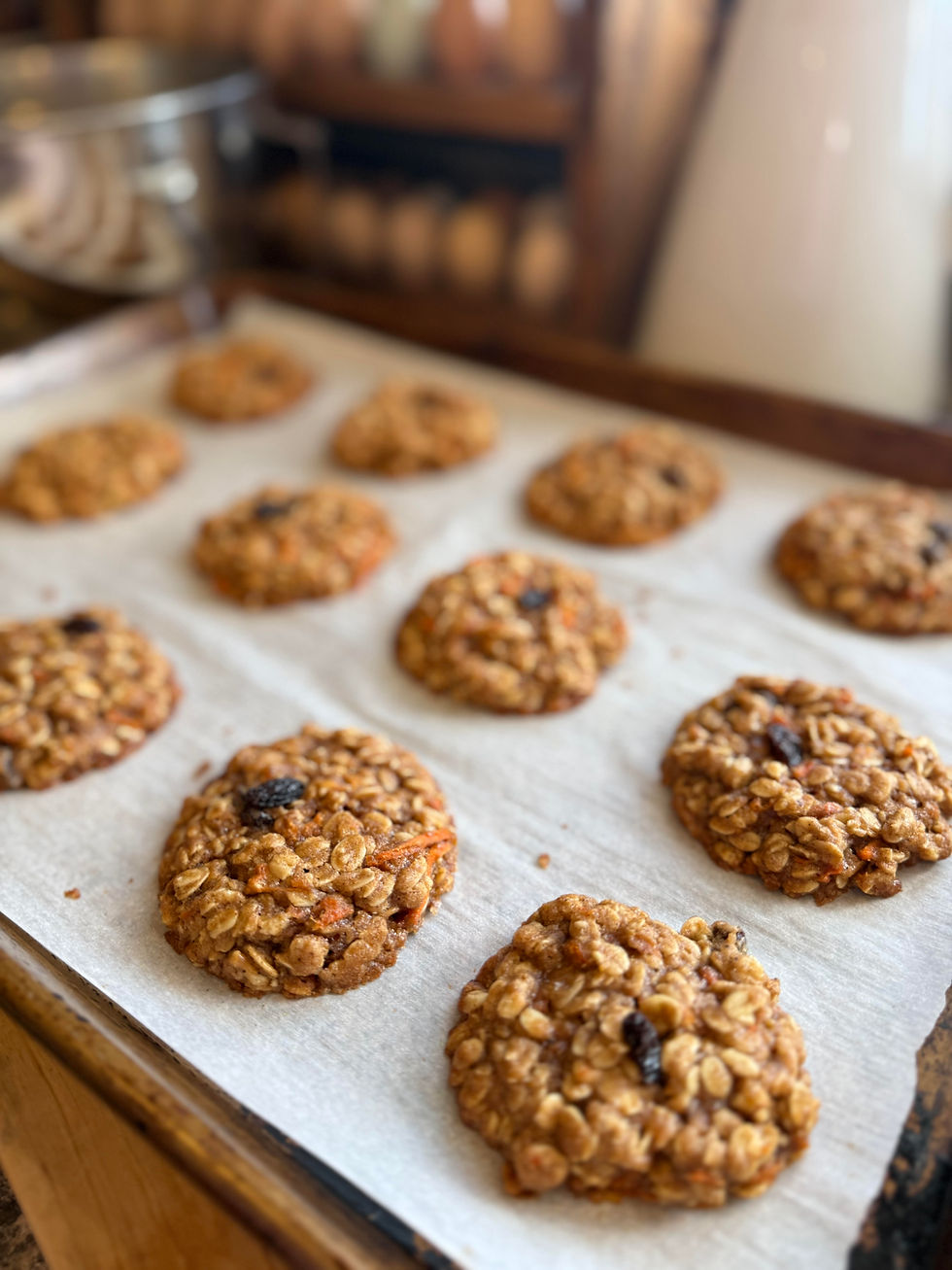 Scoops of cookie dough with orange and brown bits on parchment-lined baking sheet, in a dim kitchen setting, evoking a cozy, homemade feel.