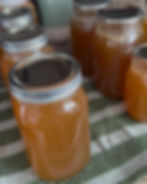 Mason jars filled with orange liquid on a green and white striped cloth. Lids labeled "Bernardin," creating a homey, preserved feel.