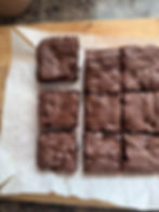 Brownies with chocolate chips, cut into squares on parchment paper. Wooden surface in background, creating a cozy, homemade feel.