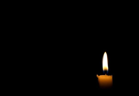uma vela acesa na escuridão sem conseguir iluminar o quarto.