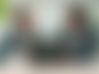 Two people sitting at a desk in front of a Laptop discussing work