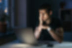 Young overworked man with laptop at night
