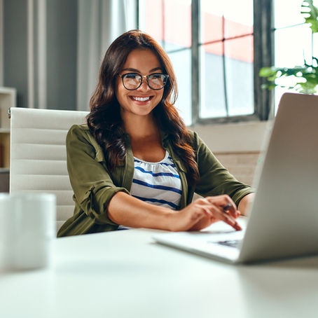 A woman sitting at her desk smiling at her computer