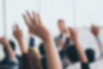 Audience raising hands up while businessman is speaking in training