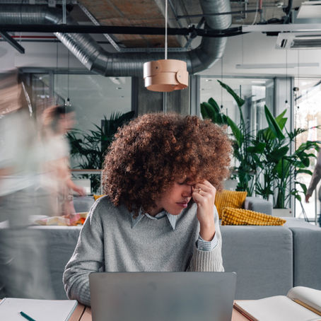 A young woman sitting at a laptop, feeling overwhelmed by stress