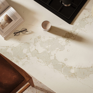 A radiant white base engineered-stone with flashes of golden hues illuminating bold veins that sweep across the surface in bands of light greys and earthy minerals with golden orange tinges, wrapped in a luxurious aura of gold.