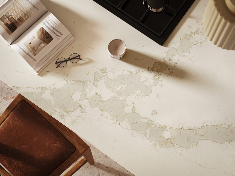 Open book, glasses, and candle on a marble countertop. Brown leather chair, stovetop, and beige textured vase in the background. Calm setting.