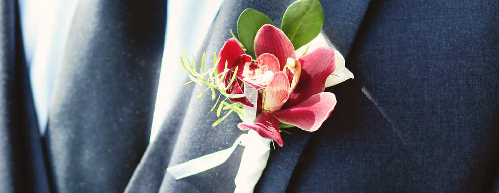 A charming image featuring the groom looking handsome with a small flower adorning his coat, adding a delightful touch of elegance to his overall appearance