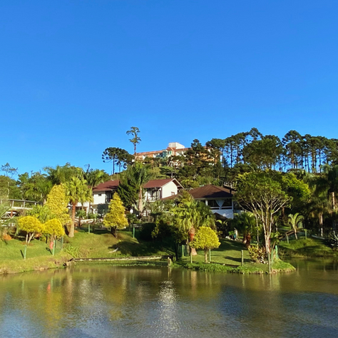 Vista do Hotel Fazenda Dona Francisca com lago, vegetação e céu azul 