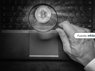Lupa enfocando una moneda de bitcoin sobre teclado portátil, símbolo de análisis de criptomonedas.