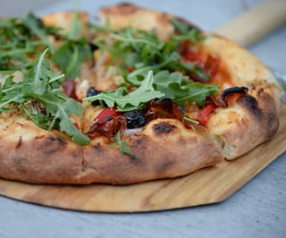 Roasted vegetable, caramelized garlic & onion pizza topped with Arugula