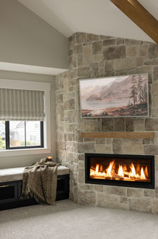 A cozy fireplace with a window seat and roman shades. 