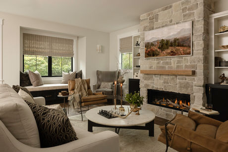 Queen Anne living room remodel with stone fireplace, neutral furnishings, and round coffee table