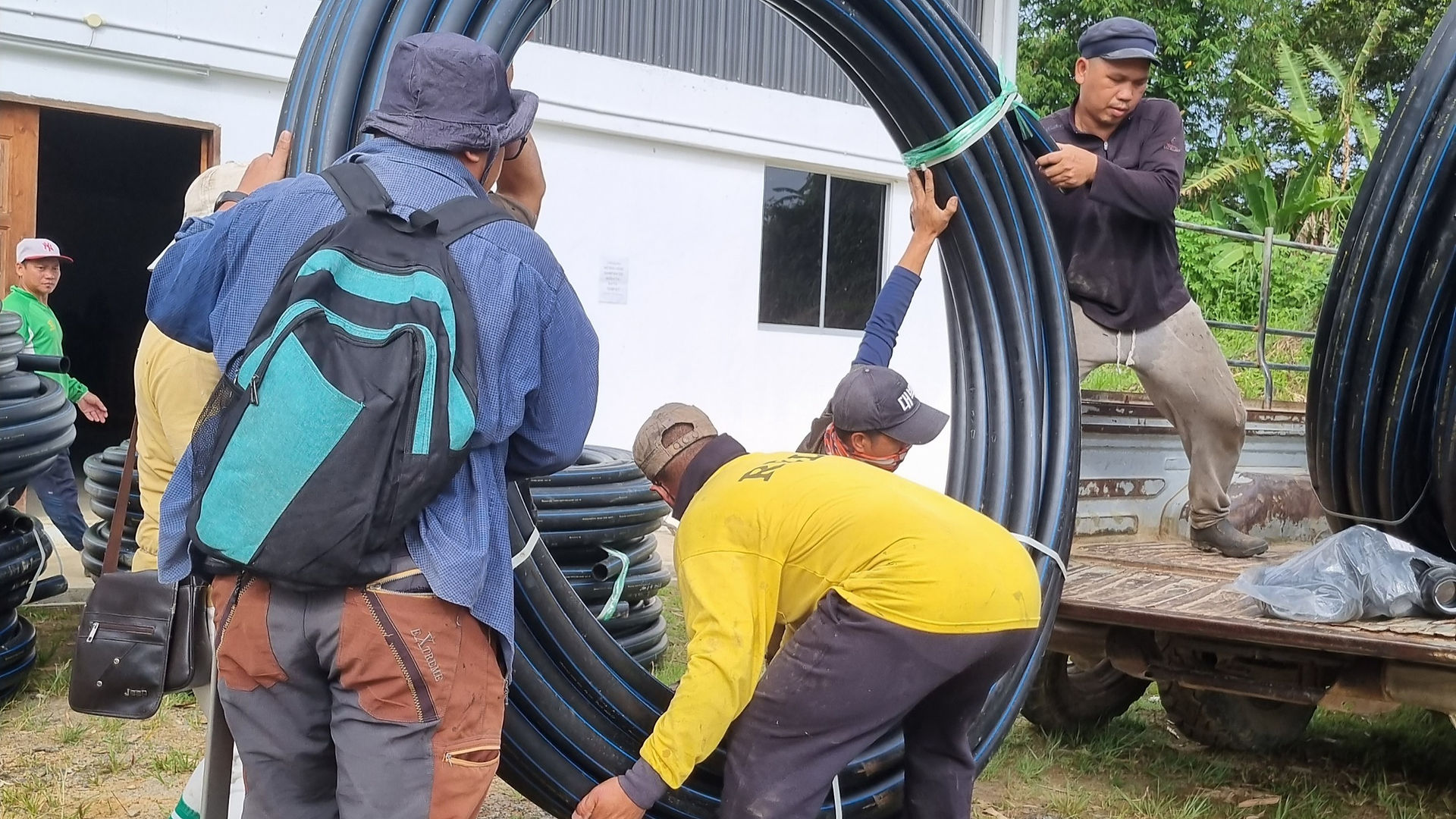 villagers loading pipes to lorry