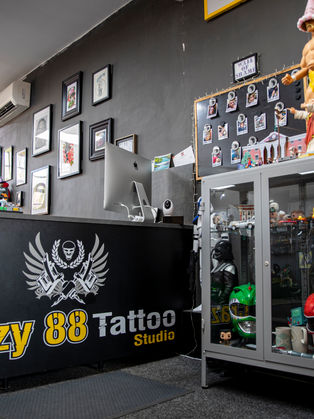 Reception desk at Crazy 88 Tattoo Studio, with some nerdy figures in a display case in the foreground and some art work on the walls in the background.