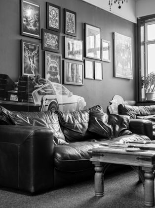 Large comfy sofa and chair in the waiting area of Crazy 88 Tattoo Studio in Retford, with a coffee table full of artists flash books as well as magazines and art books for customers to read. A warm, cozy looking environment.