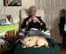 Phyllis Smith sitting in a chair holding a mug and her dog lying down in front