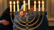 Hanukkah menorah with people hugging in background