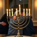 Hanukkah menorah with people hugging in background