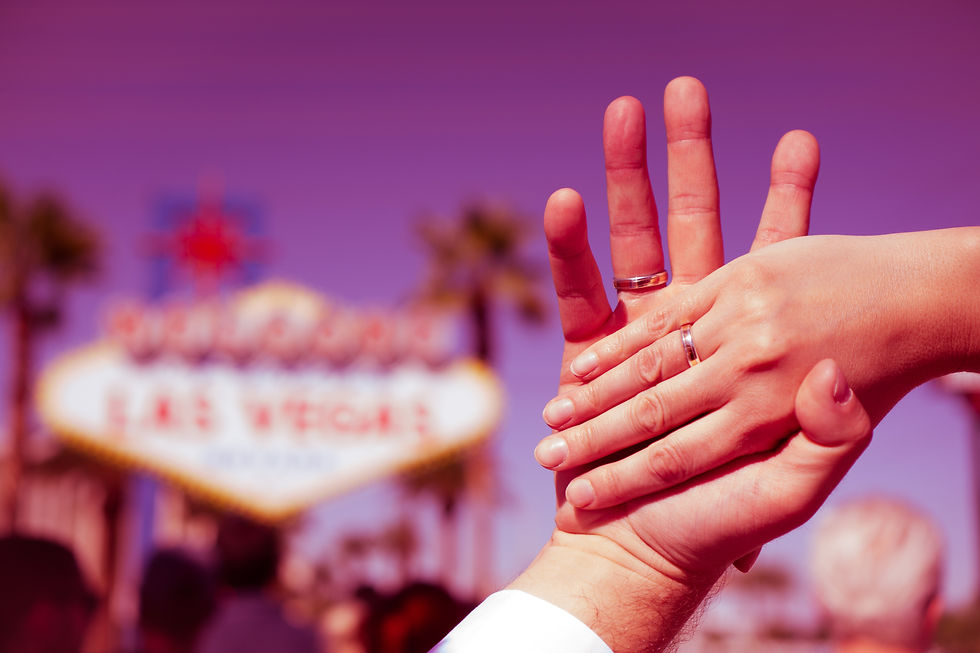 Hands joined in front of the Welcome to Las Vegas sign, showing their vow renewal rings