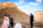 Happy couple with their parents as witnesses, listening to their bilingual wedding officiant during their ceremony at the Grand Canyon in Nevada