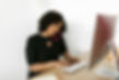 A Woman phone to ear and typing on keyboard in office