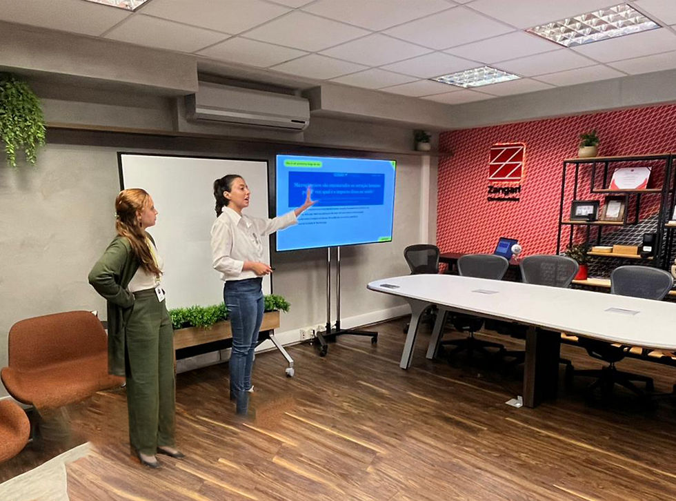 Educadoras ambientais apresentando um treinamento de conscientização ambiental, apontando para uma tela com conteúdo em azul.