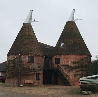 Two traditional brick oast houses with beautifully repaired white wooden cowls and Kent peg tile roofs, alongside a G&S maintenance van.