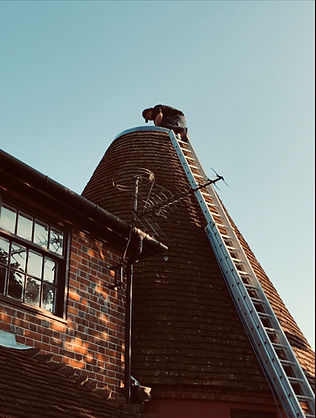 A G&S roofing expert safely working at the top of a traditional Kent oast house to perform meticulous historical restoration.